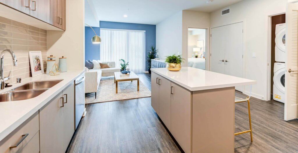 essence poi 02 A modern bedroom with a queen bed, white bedding, burnt orange curtains, dark hardwood floors, and warm neutral decor.